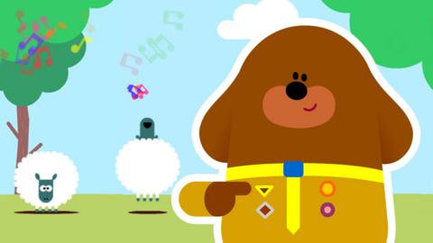 Duggee standing in front of sheep.