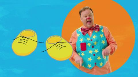 Mr Tumble is pointing and a pair of yellow shoes are next to him.