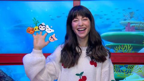 Presenter is smiling, holding up finger puppets of Octonauts characters.