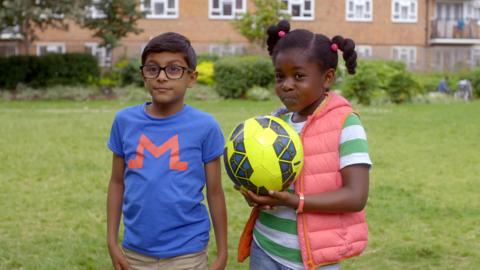 Mali alongside Sam who's holding a yellow football.