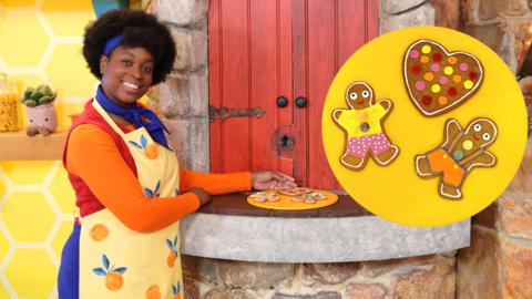 Jen (Big Cook) is standing next to the hatch displaying a plate of gingerbread friends.