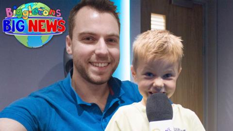 Zach from this show is holding a CBeebies Radio microphone with his dad.