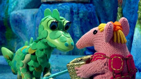 Tiny Clanger from The Clangers handing a golden box to the Soup Dragon.