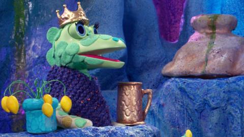 The Soup Dragon from The Clangers down in the caves wearing a crown.