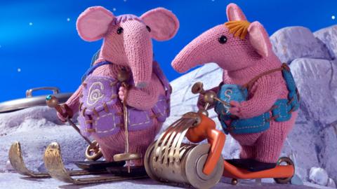 Granny and Small Clanger from The Clangers on skis and scooters.