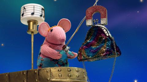 Small Clanger from The Clangers in the Music Boat hauling in a colourful bag.