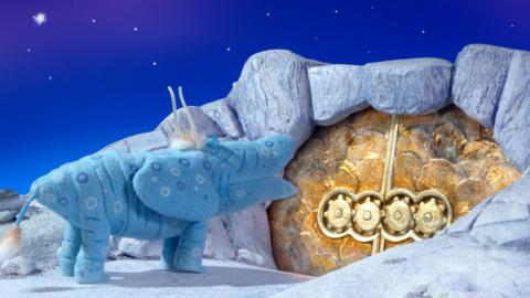 A Skymoo from The Clangers outside a cave with the doors closed.