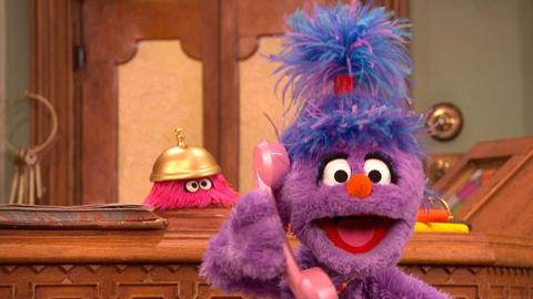 Phoebe from The Furchester Hotel on the phone at the reception desk, with Isabel.