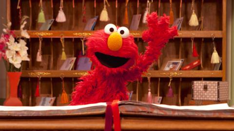 Elmo from The Furchester Hotel waving behind the reception desk.