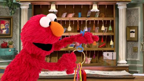 Elmo from The Furchester Hotel holding a bunch of keys at the reception desk.