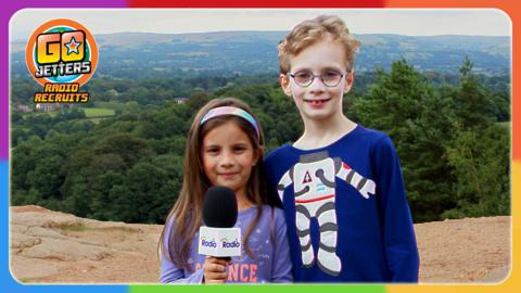 Go Jetters Radio Recruits Lena and Austen are standing at the top of Alderley Edge, with the valley of fields and houses below.