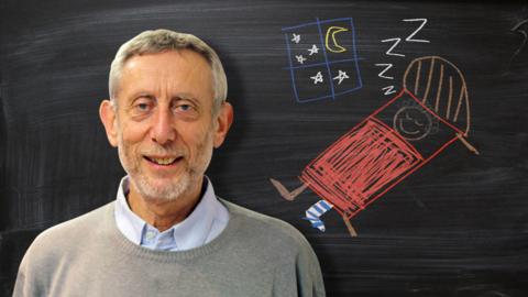 Michael Rosen from Poetry Playtime in front of a blackboard picture of a boy sleeping with one sock on.