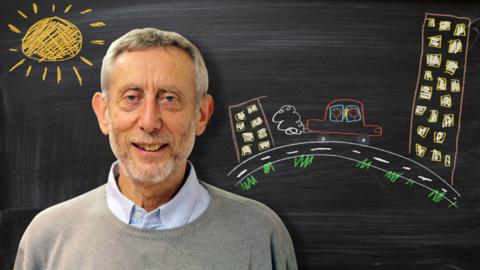 Michael Rosen from Poetry Playtime in front of a blackboard picture of a car driving near some buildings.