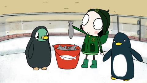 Sarah and Duck at a zoo, with Duck dressed like a penguin, feeding a penguin with a bucket of fish.