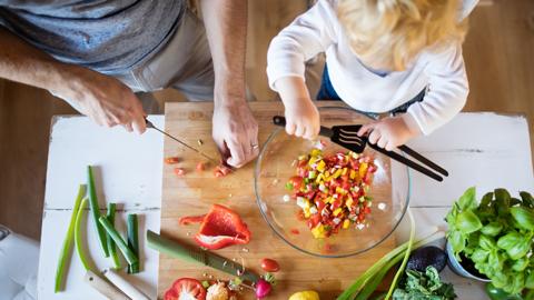 Adult and child preparing food together.