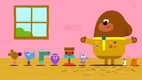 The Squirrels are standing in a row and looking at Duggee, who has his arms wide and has made the clubhouse out of little sticks.