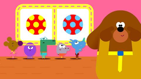 Illustration showing Hey Duggee pointing to their eyes. Whilst the squirrels are in background looking and a badge that has two different coloured balls on it to represent the spot the difference badge.