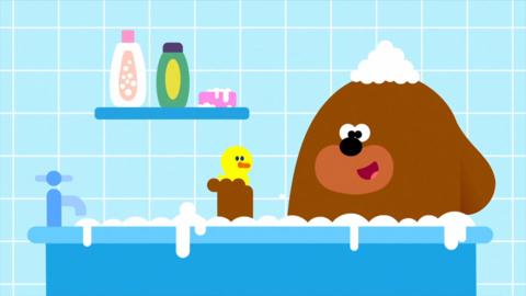 Duggie in a bath with a rubber duck