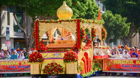 Festival float in the street surround by people.