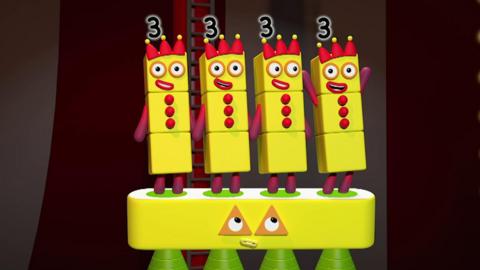 There are four numberblock three characters standing on the times table, all in yellow.