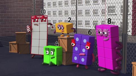Numberblocks are outside next to a fence.