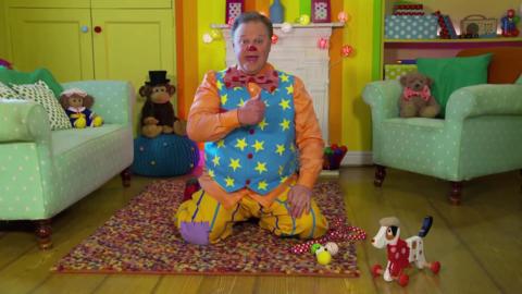 Mr Tumble plays with a toy dog.