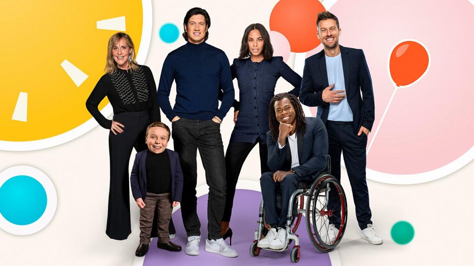 Five Children In Need presenters on a spotty background, they are: Ade Adepitan MBE, Mel Giedroyc, Rochelle Humes, Vernon Kay, Chris Ramsey and Lenny Rush.