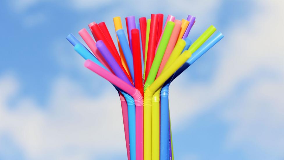 A bunch of drinking straws held up against a blue sky.