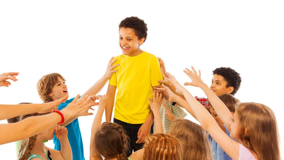 Group of children reaching up to one boy in middle