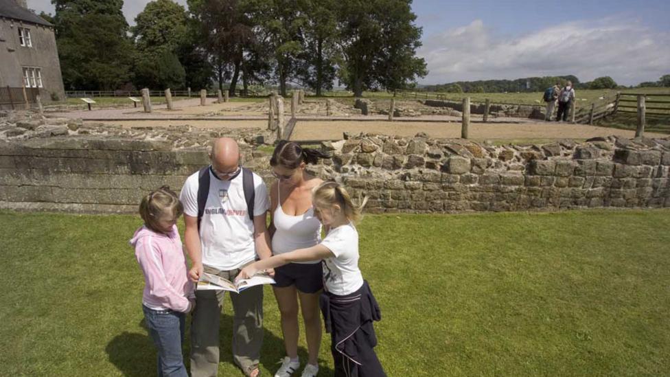 Family looking at a map , the ruins of the roman fort in the background