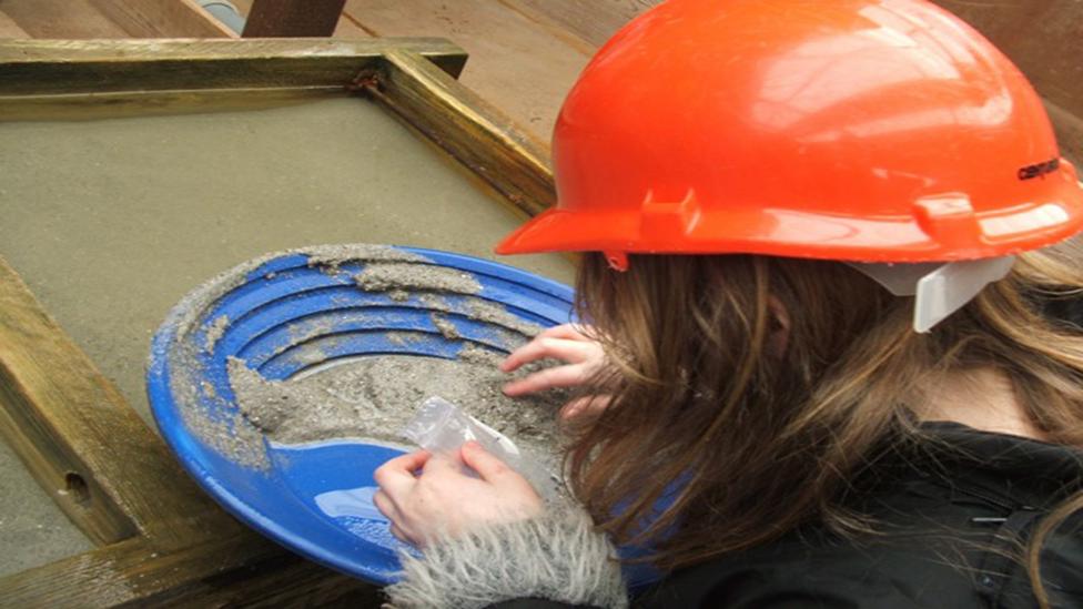 A child in a hard hat examining rock