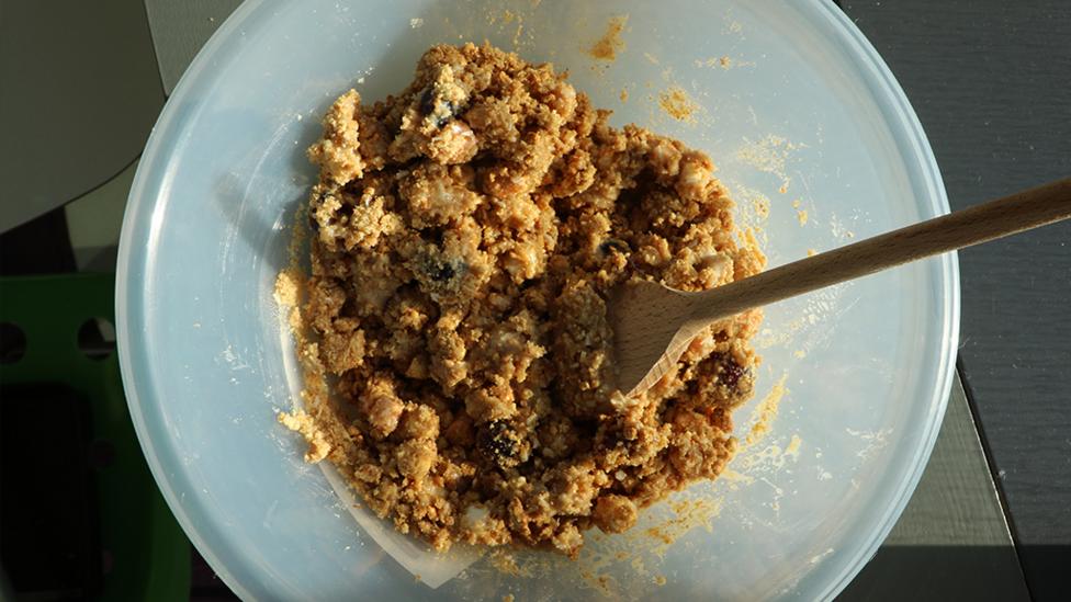 Crushed digestive biscuits, desiccated coconut, cherries, marshmallows and condensed milk all mixed together in a bowl.