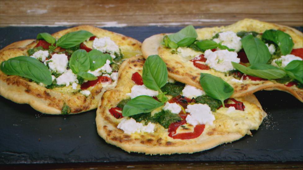 Three pizzas on a slate board.