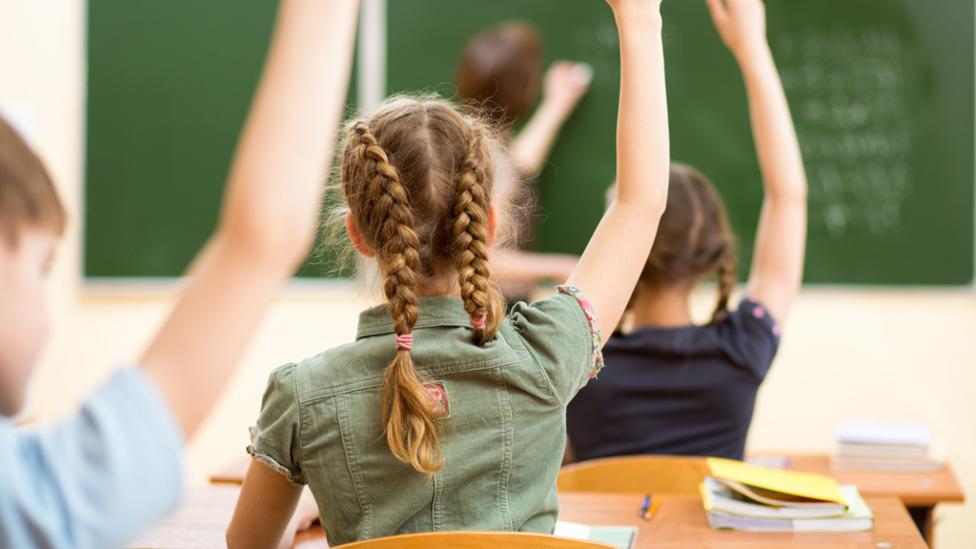 children in classroom holding arm up