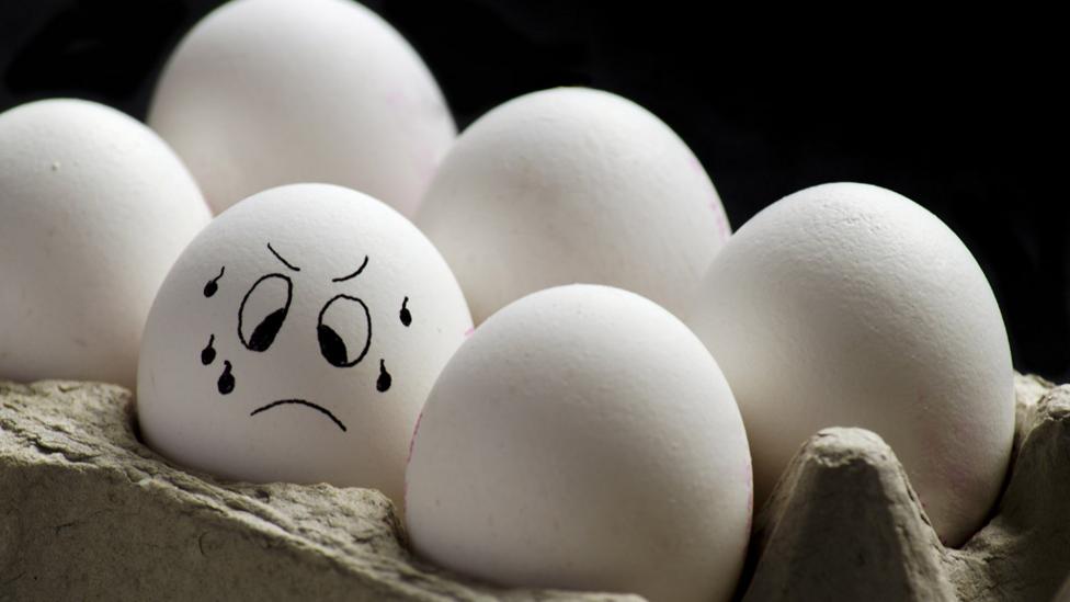 An egg in an eggbox with a worried face