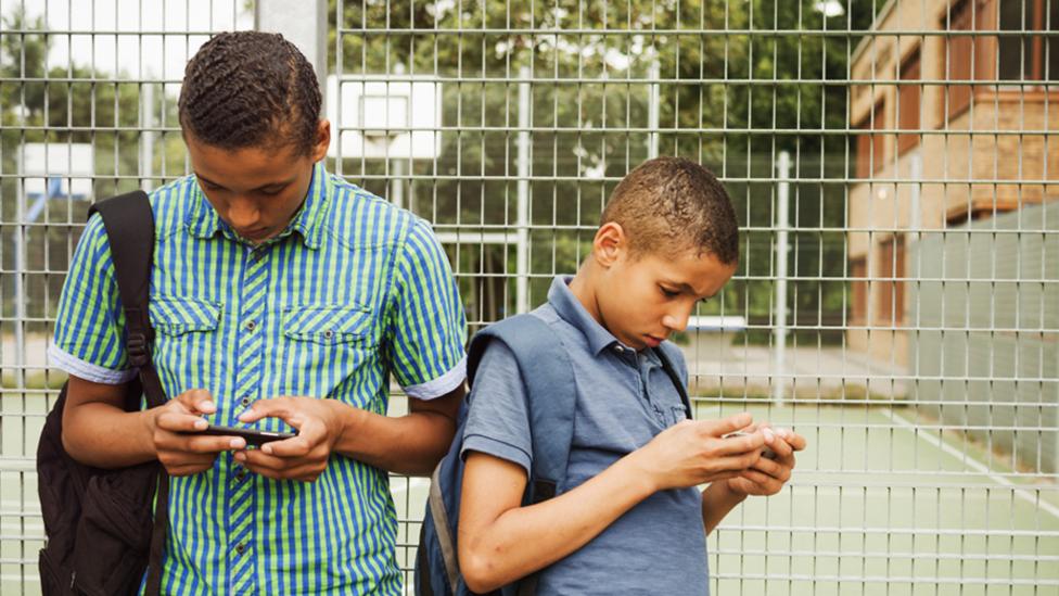 Two boys on their phones