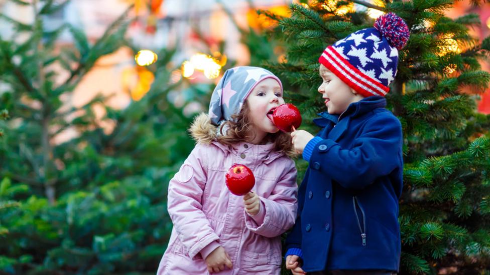 Christmas boy sharing apple with younger girl