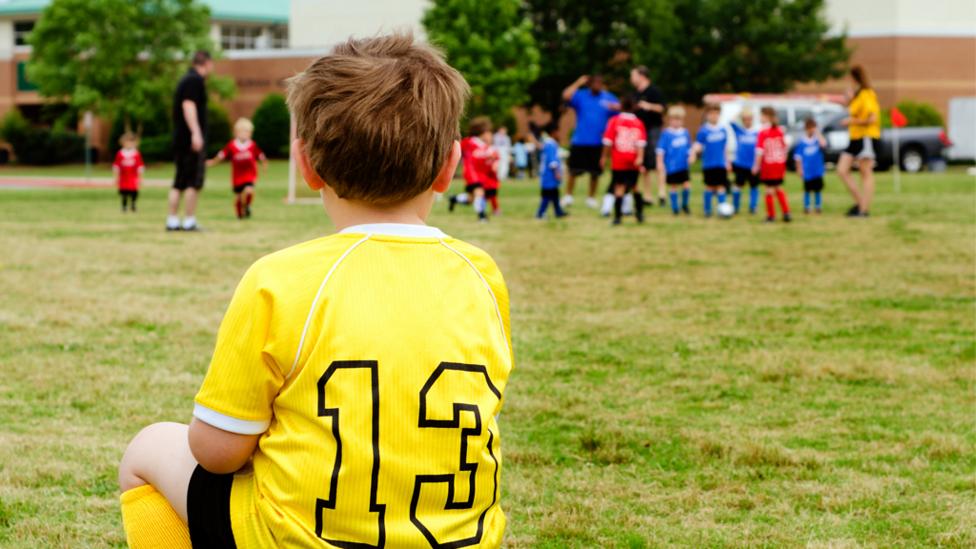 Boy sitting on bench after a football game