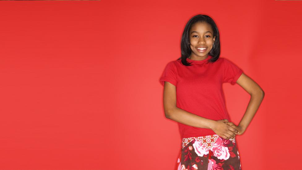 Girl standing alone against red background