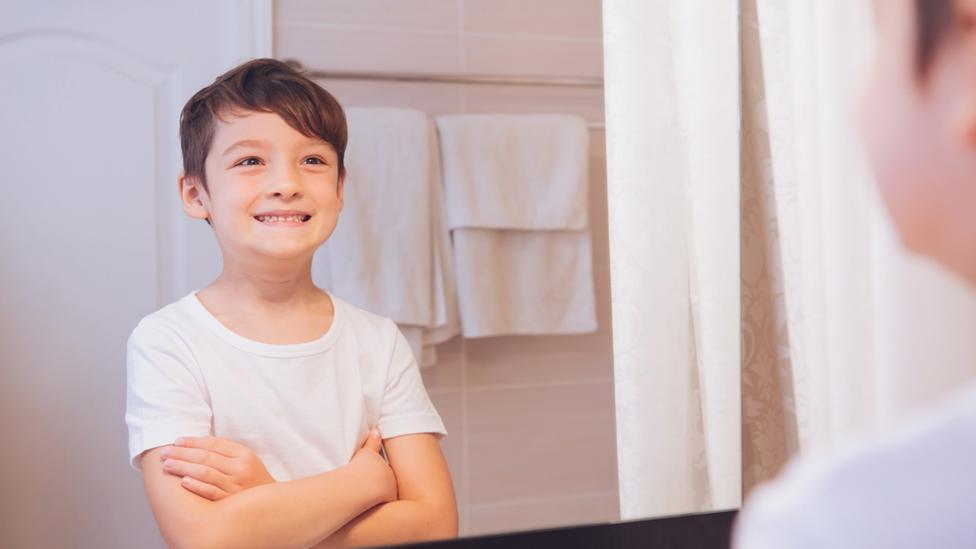 Happy boy standing in front of a mirror