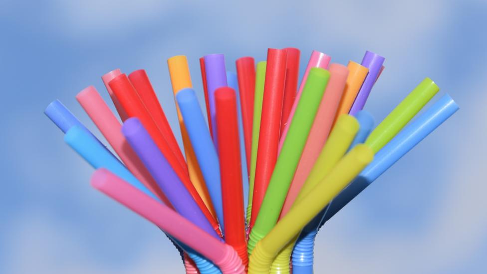 Bright multicoloured plastic straws with a blue sky background.