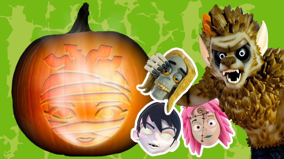 A large pumpkin carved with a minalmist of the Mummy character from the show, Cleo. Next to that is a large werewolf, he is holding a mask of a zombie's head with tow masks behind it - a vampire and a frankenstein girl