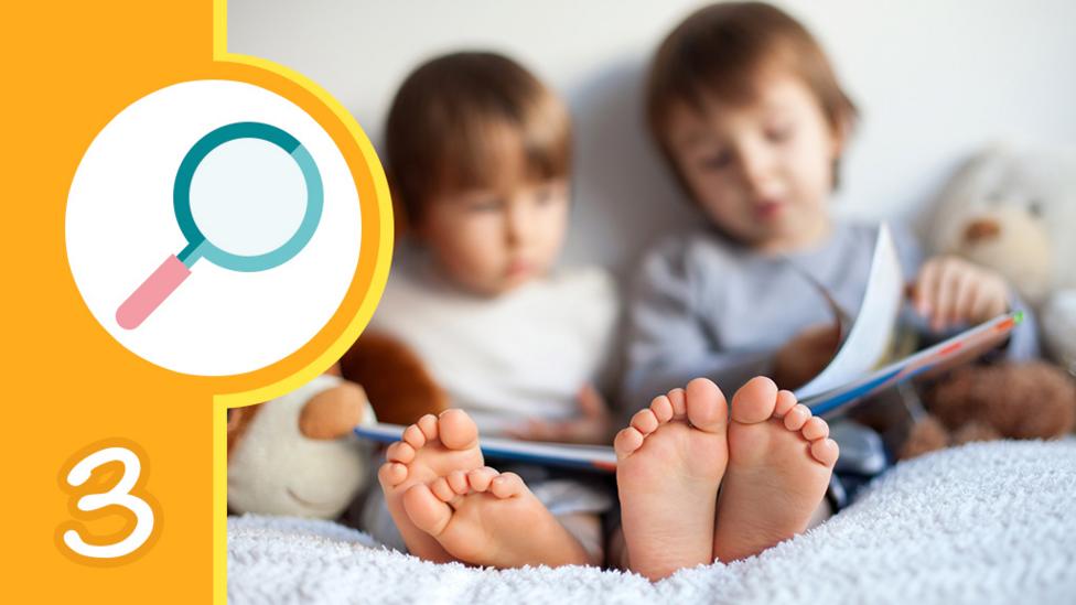 Two children sat reading a book together and a graphic of a magnifying glass