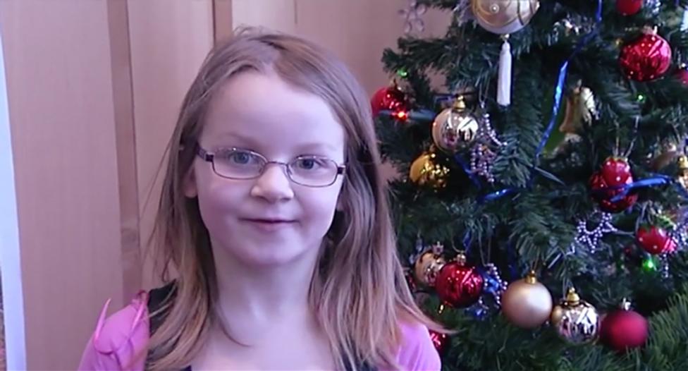 girl standing in front of a Christmas tree