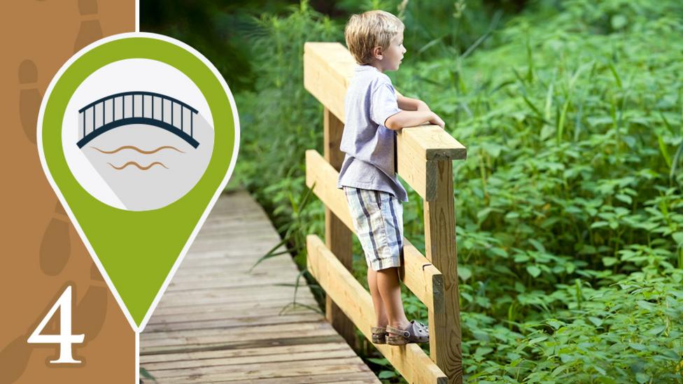 A boy stood on a footbridge and looking over the edge