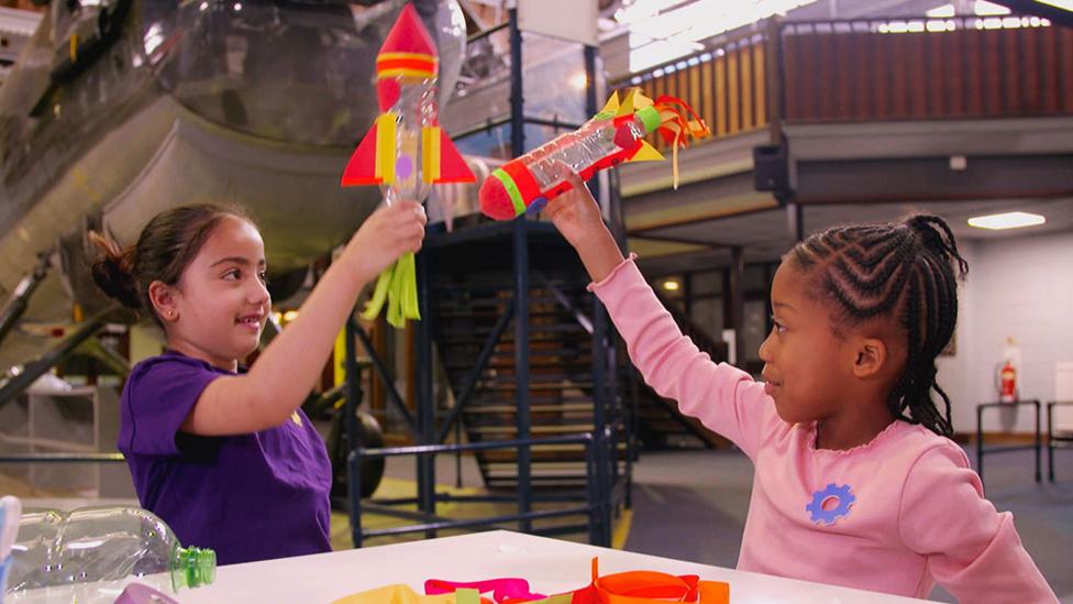 Two children playing with a pair of rockets