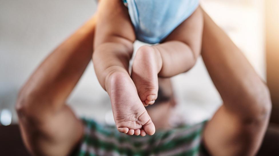 Shot of an unrecognizable little boy being lifted up by his dad while being seated on a sofa at home during the day