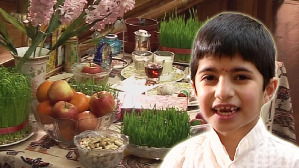 Boy standing in front of a table with various food and plants on it