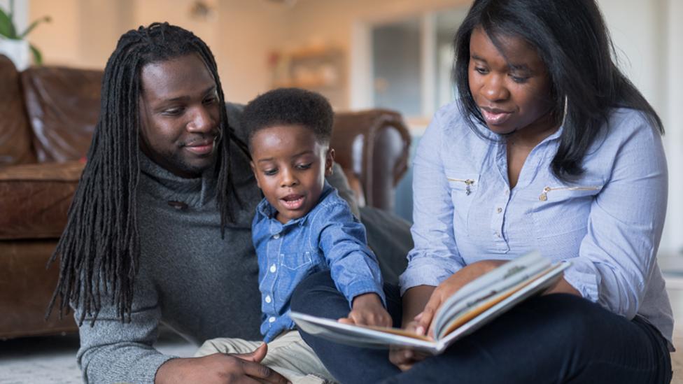 Mother and father reading to their son.