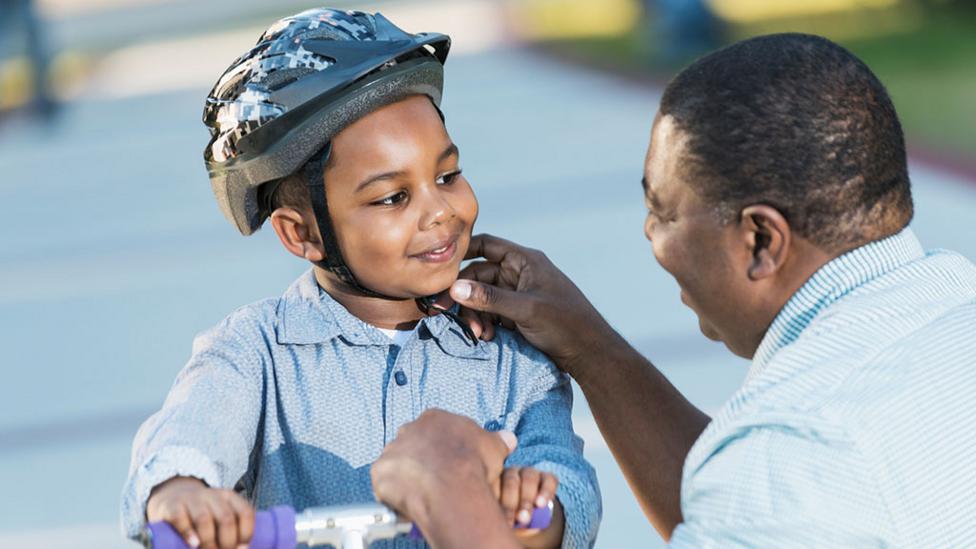 A parent checking their child's helmet.